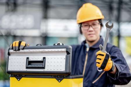 Male Asian mechanic or maintenance worker man wearing protective suit and helmet opening work tool...