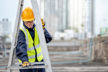 Asian maintenance worker man with safety helmet and reflective suit adjusting aluminium step ladder...