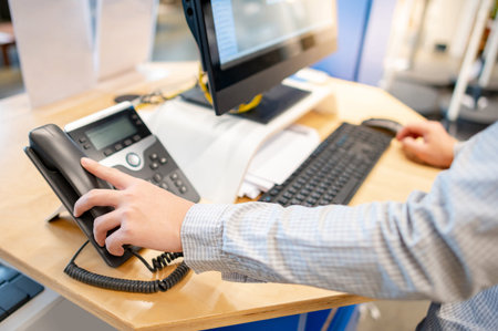 Male customer support operator hand trying to response customer call by using landline phone on...