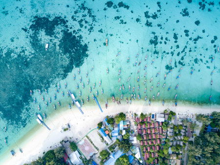 Stunning summer landscape. Aerial view of fishing long tail boat group in turquoise Andaman sea near white beach and resort at Koh Lipe or Lipe island, Satun, Southern Thailand. Shot from droneの写真素材