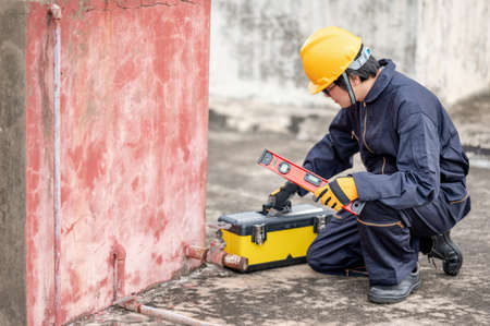 Male Asian mechanic or maintenance worker man wearing protective suit and helmet opening work tool box at construction site. Equipment for mechanical engineering projectの写真素材