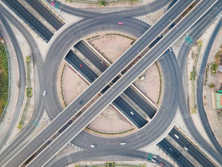 Aerial view of road intersection with roundabout. Urban highway interchange with cars speeding. Junction network of transportation taken by drone.の写真素材