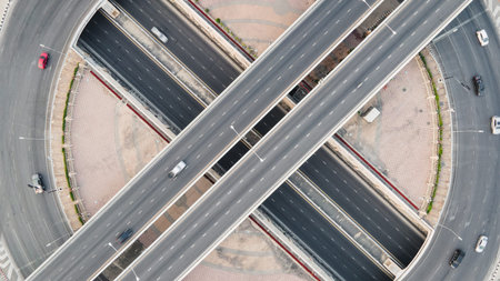 Aerial view of road intersection with roundabout. Urban highway interchange with cars speeding....
