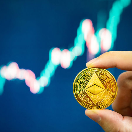 Hand holding gold ETH coin with blurred candlestick chart in the background. Ethereum is a...