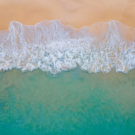 Aerial view of turquoise ocean wave reaching the coastline. Beautiful tropical beach from top view....