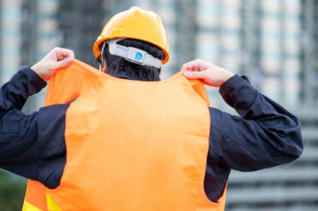 Asian maintenance worker man wearing reflective vest and safety helmet working at construction site. Civil engineering, Architecture builder and building service conceptsの写真素材