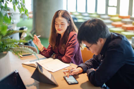 Business meeting and partnership concept. Attractive Asian businesswoman talking to colleagues about project at workplace. Coworkers team having conversation sharing ideas together in conference room.の写真素材