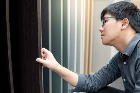 Asian man choosing cabinet panel materials or countertops for built-in furniture design. Shopping furniture and decoration. Home improvement conceptの写真素材