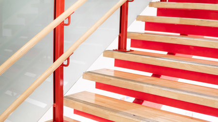 Wooden stair step ladder on red steel staircase structure with glass railing. Architectural element designの写真素材