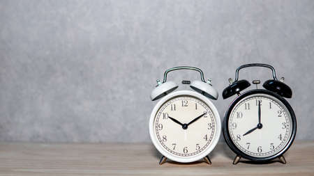 White and black classic analog alarm clock on wooden table. Time management conceptの写真素材