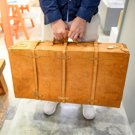 Male hand carrying antique leather suitcase. Old vintage suitcase for travel and business. Retro...