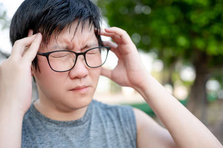 Asian man athlete feeling dizzy and tired while doing outdoor exercise in the park. Sport overtraining or Heat stroke conceptの写真素材