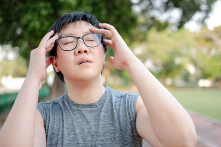 Asian man athlete feeling dizzy and tired while doing outdoor exercise in the park. Sport overtraining or Heat stroke conceptの写真素材