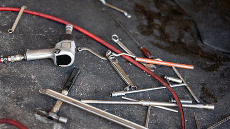 Many auto mechanic tools. Car suspension fixing and tire changing in the garage. Pneumatic wrench, spanner, hammer, screwdriver and other mechanical work tools on concrete floor in auto repair shopの写真素材