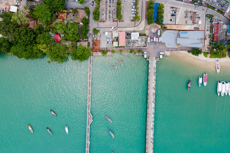 Aerial view of Ao Chalong Bay shoreline with 2 bridges and boats anchored around. One is a local pier with a dolphin floor pattern and another one is a vehicle way to Chalong Pier in Phuket, Thailand.の写真素材