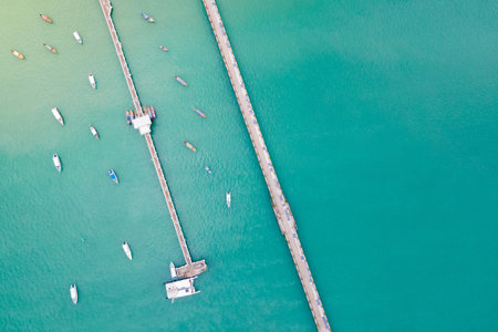 Aerial drone view of 2 bridges with tour boats anchored around at Ao Chalong Bay. One is a local pier with a dolphin floor pattern and another one is a vehicle way to Chalong Pier in Phuket, Thailand.の写真素材