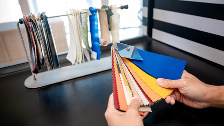 Fabric swatch material choice. Designer hand choosing fabric sample pieces from color collection for...