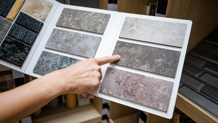 Flooring material design collection. Designer hand pointing at stone tile sample on display catalog....