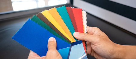 Fabric swatch material choice. Designer hand choosing fabric sample pieces from color collection for...