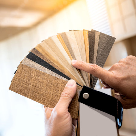 Designer hand pointing at sample of wood laminated material from natural collection. Customer choosing wooden veneer texture or set of MDF board swatch fan for interior finishing or furniture designの写真素材
