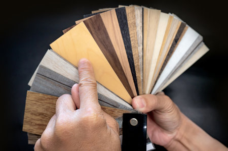 Designer hand pointing at sample of wood laminated material from natural collection. Customer choosing wooden veneer texture or set of MDF board swatch fan for interior finishing or furniture designの写真素材