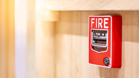 Red fire alarm switch mounted on wooden wall in the office interior. Fire warning system equipment for emergency and evacuation in public buildingの写真素材