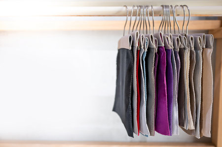 Set of colorful fabric swatch material. Various color and texture upholstery sample collection hanging on wooden showcase rack. Textile industry for home interior design and furniture finishing decorの写真素材