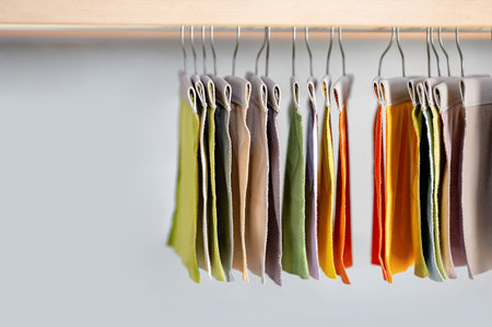 Set of colorful fabric swatch material. Various color and texture upholstery sample collection hanging on wooden showcase rack. Textile industry for home interior design and furniture finishing decorの写真素材