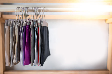 Set of colorful fabric swatch material. Various color and texture upholstery sample collection hanging on wooden showcase rack. Textile industry for home interior design and furniture finishing decorの写真素材