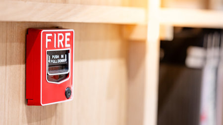 Red fire alarm switch mounted on wooden wall in the office interior. Fire warning system equipment for emergency and evacuation in public buildingの写真素材