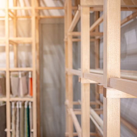 Modern wooden showcase rack with blurred fabric swatch materials hanging in the background. Interior furniture design for product display in exhibition or shopの写真素材