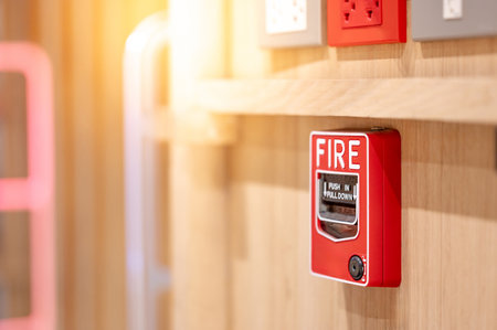 Red fire alarm switch mounted on wooden wall in the office interior. Fire warning system equipment for emergency and evacuation in public buildingの写真素材