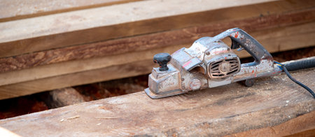 Rustic old electric planer on timber stack or wooden plank with sawdust spreading around. Work tool for carpentry. Lumber industry conceptの写真素材