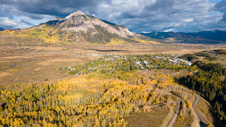 Aerial view of beautiful fall foliage landscape during golden sunset at Crested Butte, a town in the Rocky mountains, Colorado, USA. Yellow aspen forest and winding road. Scenic autumn seasonの写真素材