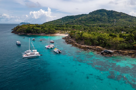 Aerial view of Racha Yai Island or Koh Raya with tour boats, yacht, catamaran and longtail boat anchoring around the bay. A popular destination for summer vacationの写真素材