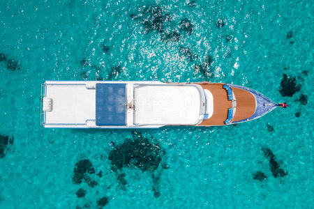 Aerial view of scuba diving boat or recreational vessel anchoring over turquoise clear water at...