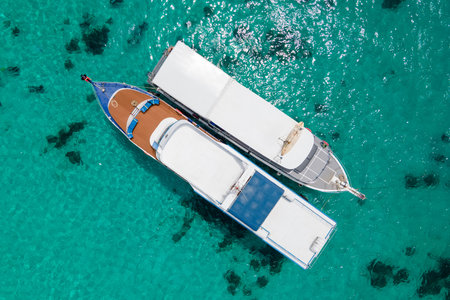 Aerial view of two recreational vessels or scuba diving boat anchoring together over turquoise clear water at Racha Island or Koh Racha, A popular destination for summer vacation in Phuket, Thailand.の写真素材