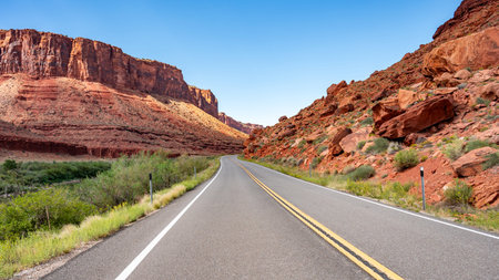 Empty scenic country road with stunning view of eroded red sandstone landscape at both sides in...