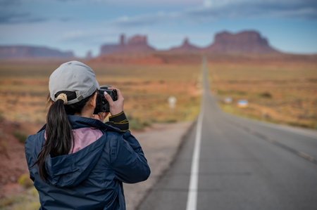 Rear view of Asian female tourist holding camera taking a popular shot at Forrest Gump Point on US...