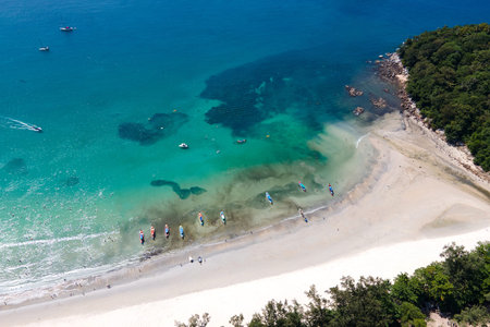 Aerial view of tropical shoreline with longtail boats anchoring in turquoise water bay at Kata Beach, a famous summer destination in Phuket, Thailand.の写真素材