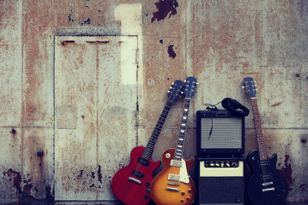 Group photo of an electric guitar placed on the door of a rusted iron warehouseの写真素材