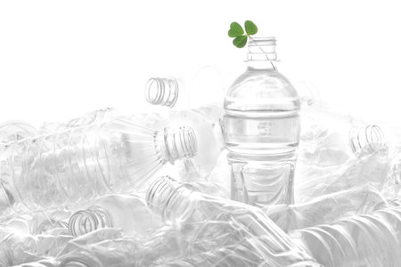 Lots of plastic bottles and green leaves piled up on white background