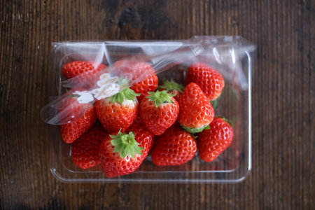 Strawberry in plastic bag on wooden background. Top view.の写真素材