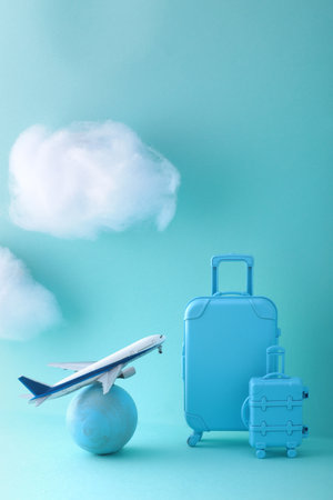 Image of an international trip on a blue background with model of an airplane, suitcase and cloudsの写真素材