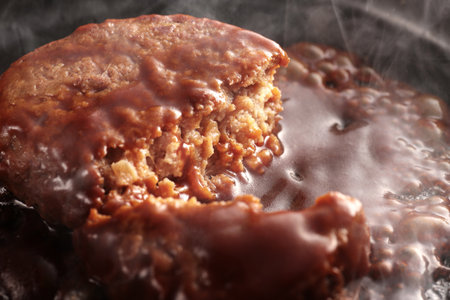 Juicy hamburger steak cooked on a hot iron plate, steaming hotの写真素材