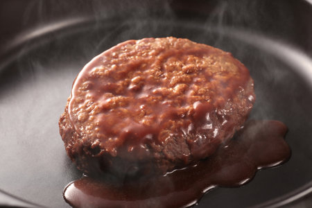 Juicy hamburger steak cooked on a hot iron plate, steaming hotの写真素材