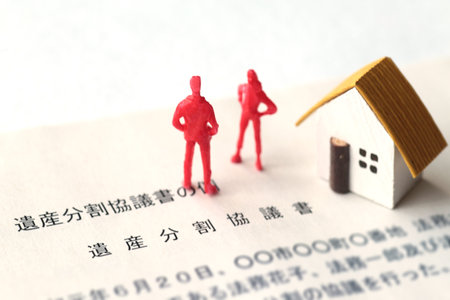 A photo showing inheritance troubles using miniature dolls, a house, and textの写真素材