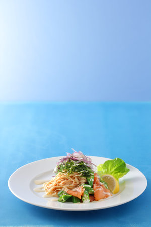 A spring or summer image of a plate of pasta with sunlight shining on it, placed against a colorful backgroundの写真素材
