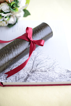 Graduation certificate, graduation album and cherry blossom petalsの写真素材