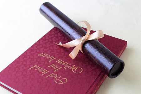 Graduation certificate, graduation album and cherry blossom petalsの写真素材